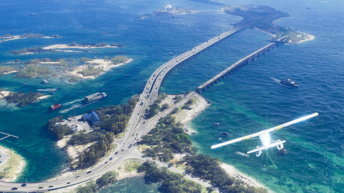 A plane flies over a bay area of Vice City, above roads connecting small islands.