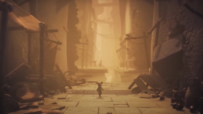 A Little Nightmares 3 screenshot showing one of its two protagonists walking along the sandy streets of a ruined ancient city, collapsed market stalls on either side.