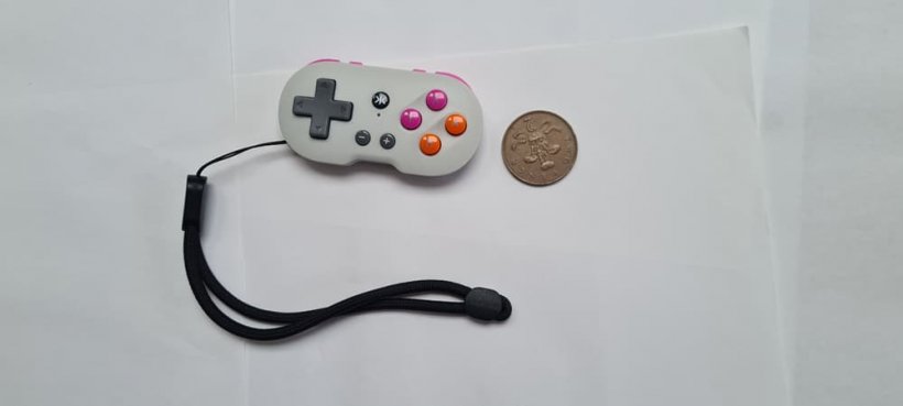 A picture of the CRKD Atom, a small controller, next to a coin for scale