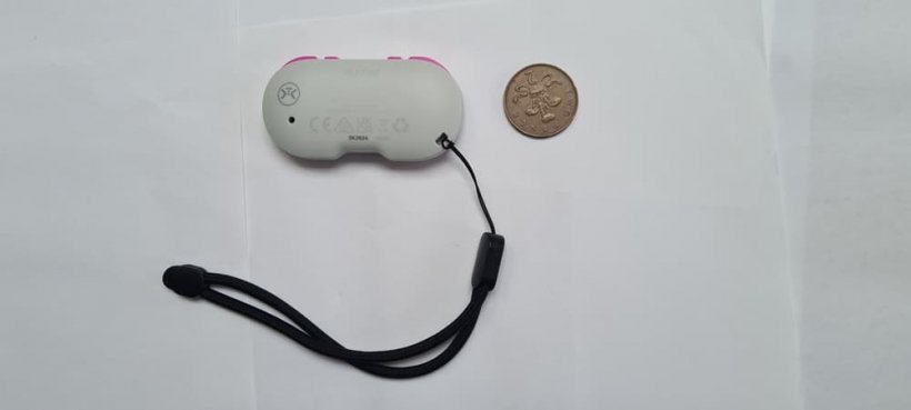 The backside of the CRKD Atom, a small controller, with coin for scale