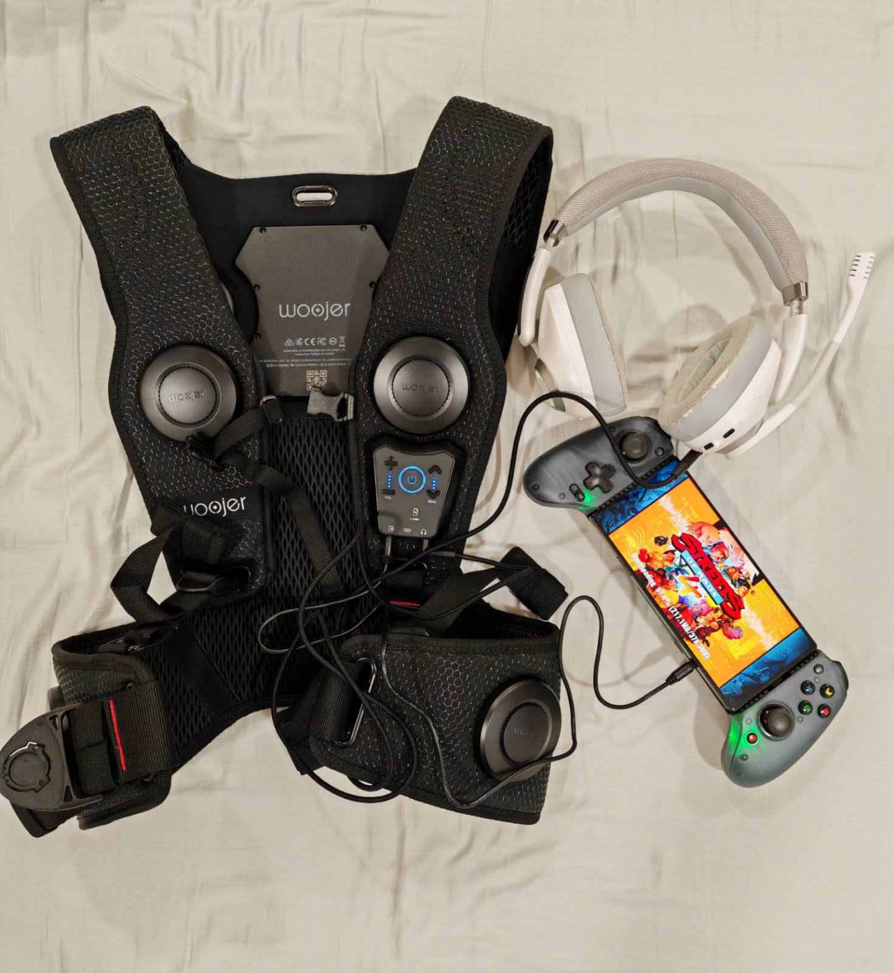 the woojer vest 3 with headphones and a streets of rage game on a phone