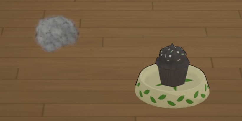 close up of a dust cupcake in a food bowl on a wooden floor. A dustbunny is to the left