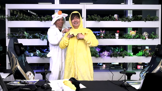 Final Fantasy 14's Naoki Yoshida in a yellow chocobo onesie and Toshio Murouchi in a white moogle onesie