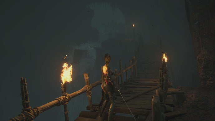 Wuchang stands on an unstable wooden bridge in an underground, dark cave, in a screenshot from Wuchang Fallen Feathers.