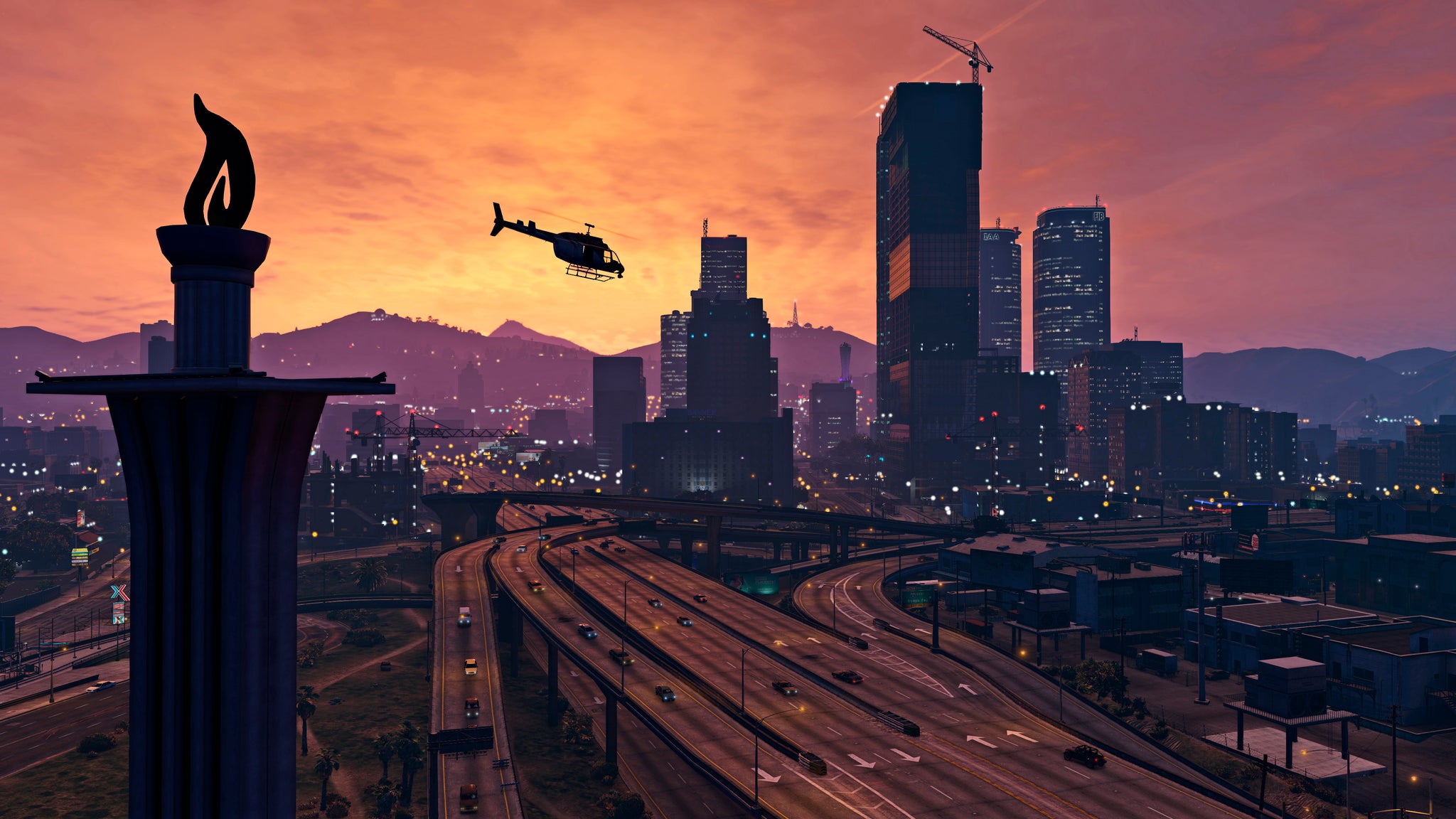 Official GTA 5 image showing a helicopter flying over a bustling highway against downtown Los Santos at sunset